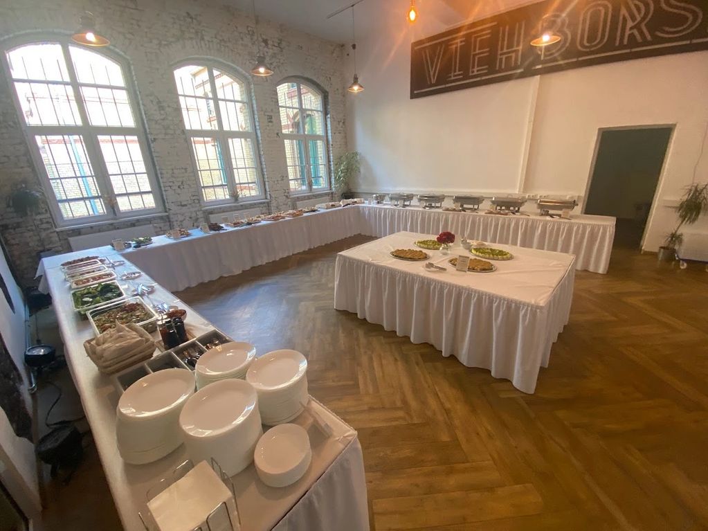 Elegant buffet setup in a spacious room with rustic windows and wooden floors.