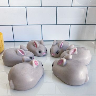 Six gray bunny shaped soaps all facing each other in a circle on a bathroom counter