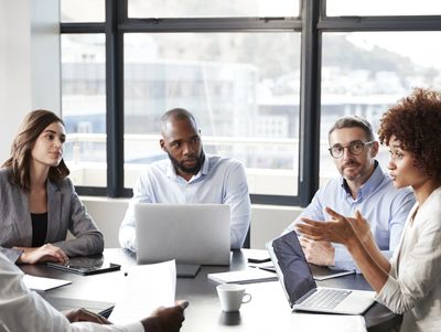 A diverse business team engaged in a discussion around a conference table.