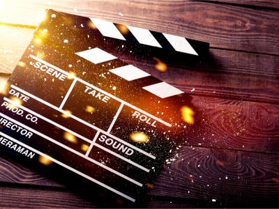 A classic black and white movie clapperboard on wooden surface with light effects.