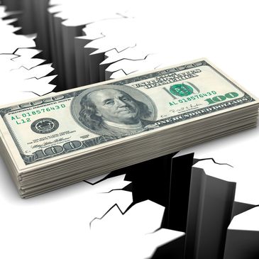 Stack of hundred-dollar bills over a cracked surface.