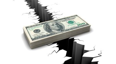 Stack of $100 bills bridging a deep crack in the ground.