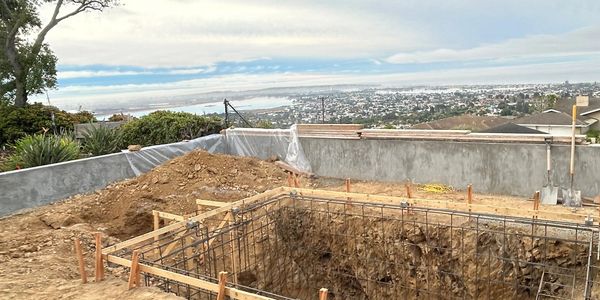 Construction site with rebar framework and city view in the background.
