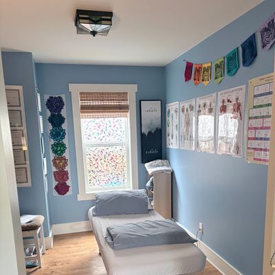 A calm therapy or massage room with blue walls and anatomy charts.