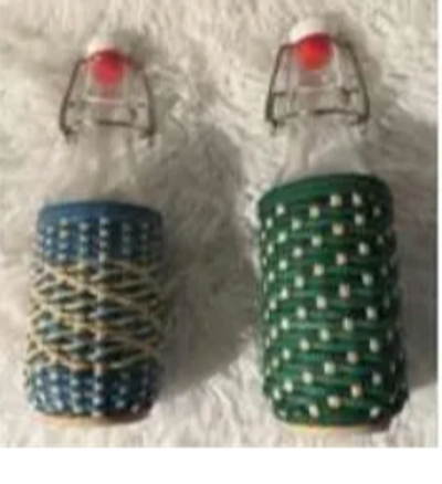 Two glass bottles wrapped with colorful string and capped with a red top.