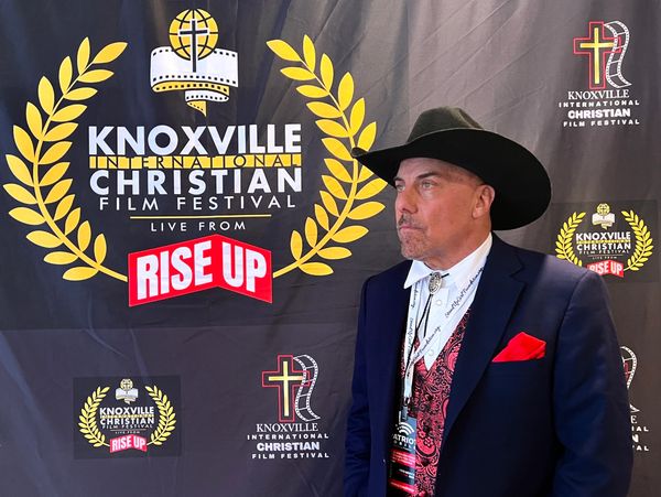Man in cowboy hat at Knoxville Christian Film Festival backdrop.
