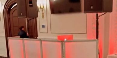 Indoor event setup with illuminated DJ booth and speakers.