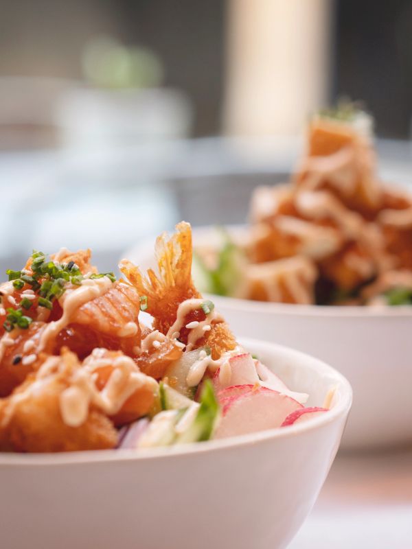 Close-up of a seafood poke bowl with sauce and garnishes.