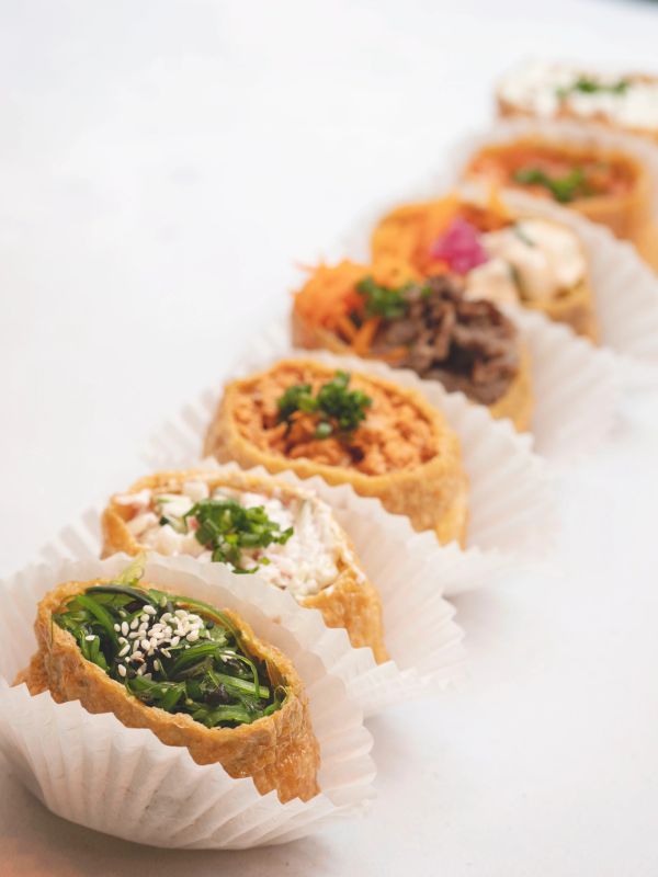 Assorted sushi rolls on white paper cups.