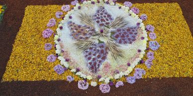 Decorative floral rangoli with purple, yellow, and white flowers.