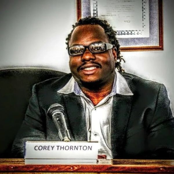 Man named Corey Thornton sitting behind a microphone at a panel or conference.