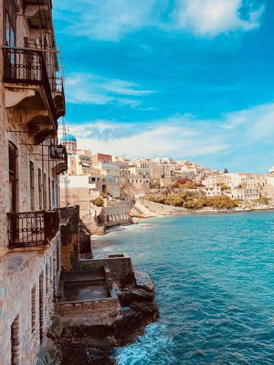 Coastal town with stone buildings and clear blue sea under a bright sky.