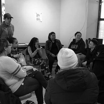 Group of people engaged in a discussion in a casual indoor setting.