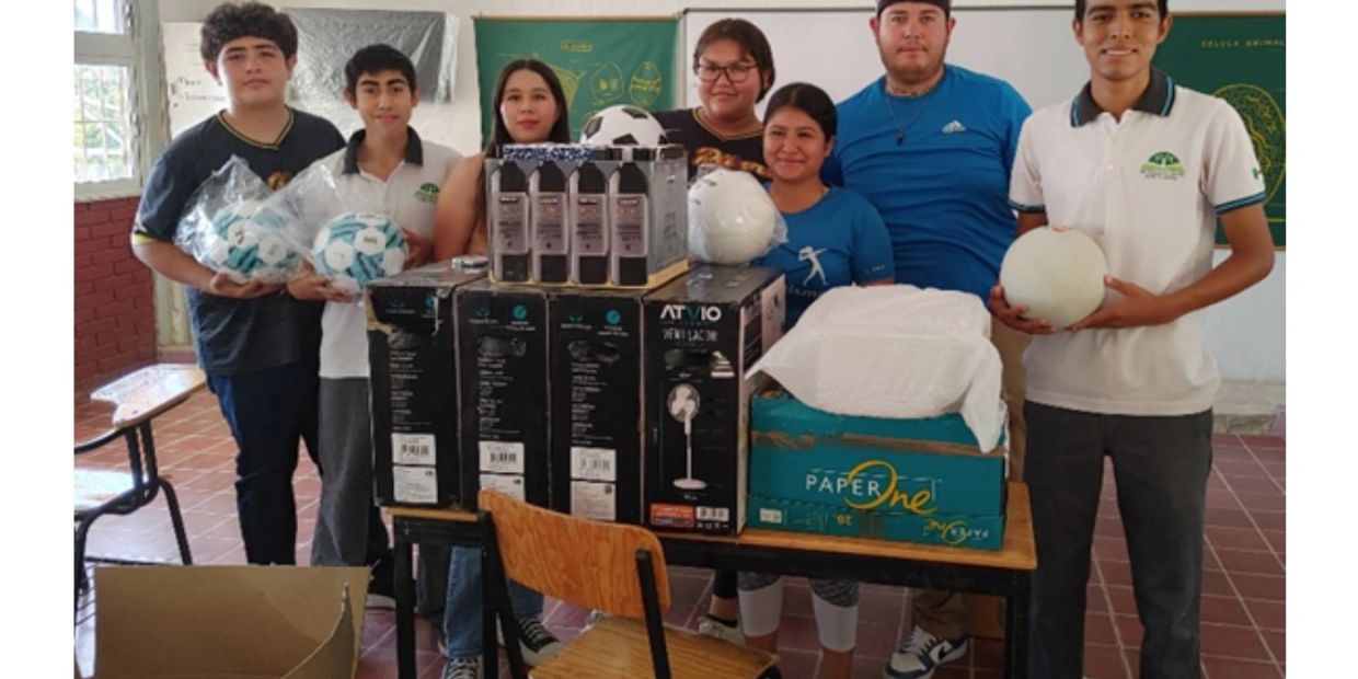Group of young people with donated supplies including soccer balls and fans.