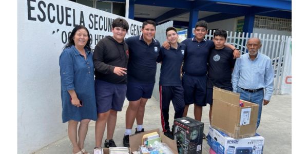 Group of students and teachers with school supplies outside.