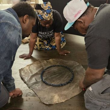 Three people examining an artifact on the floor.