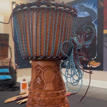 Handcrafted wooden drum with colorful strings.