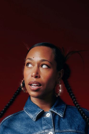 Woman with braided hair and hoop earrings looking up.
