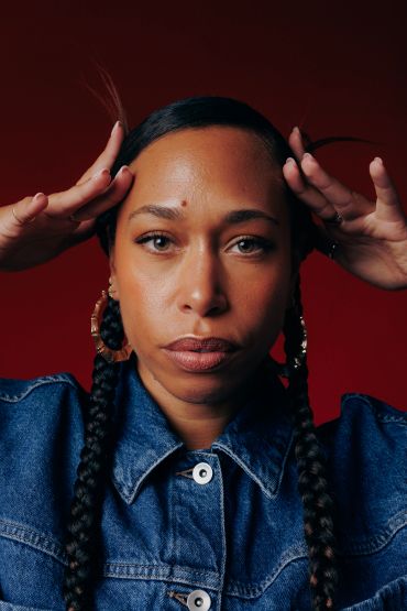 Woman with braided hair wearing a denim jacket.