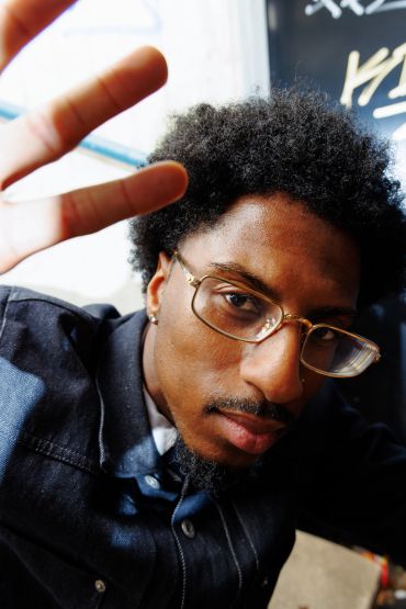 Young man with glasses raising his hand toward the camera.