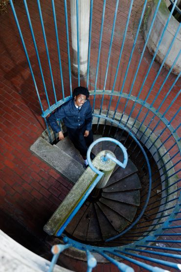 Man standing on a spiral staircase looking up.