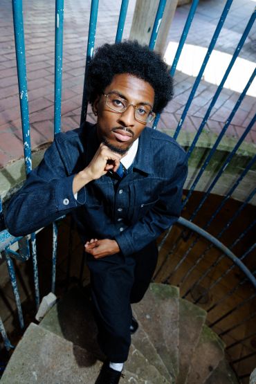 Young man with glasses on spiral staircase.
