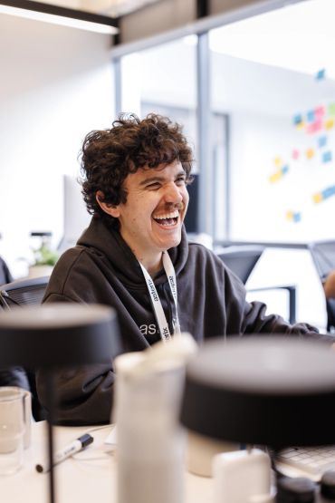 Young man laughing in a bright office.