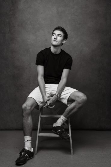 Young man sitting on a stool in a studio.