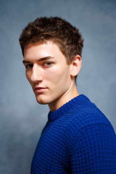 Young man in a blue sweater looking sideways.
