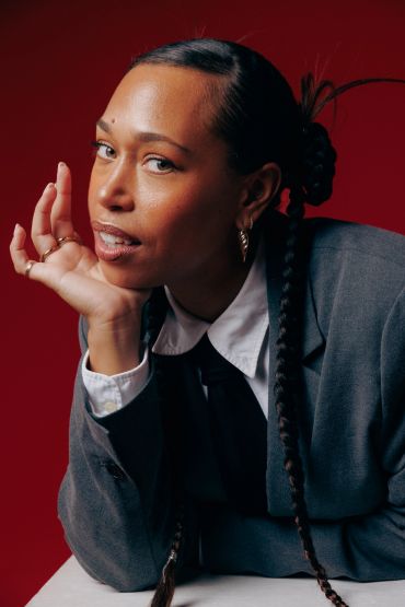Confident woman posing against a red background.