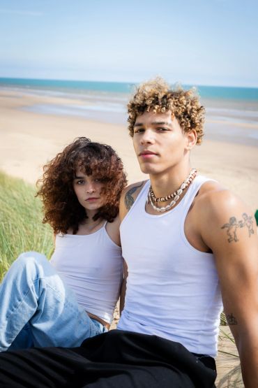 Young couple in white tank tops at the beach with ocean background.