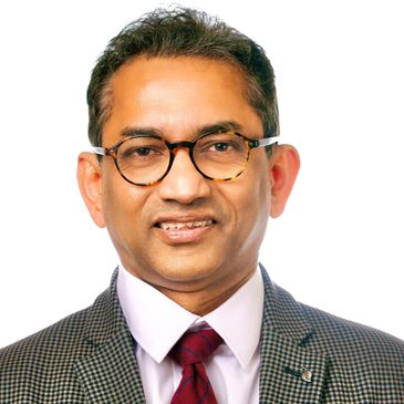Portrait of a smiling man in glasses and formal attire.