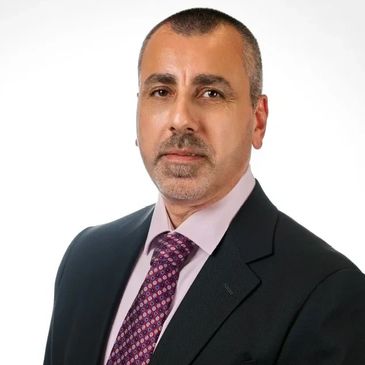 Professional man in suit and patterned tie against white background.