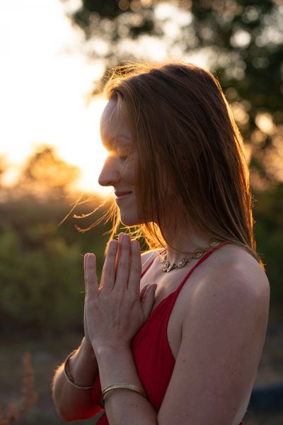 Woman in red meditating at sunset.