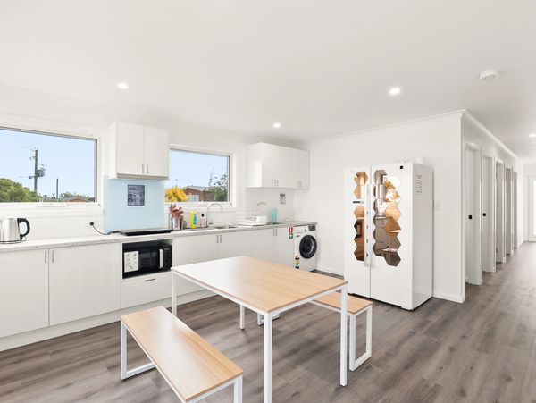 Modern kitchen with white cabinets and wooden dining table with benches.