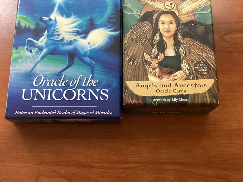 Two oracle card decks, one featuring a unicorn and the other angels and ancestors.
