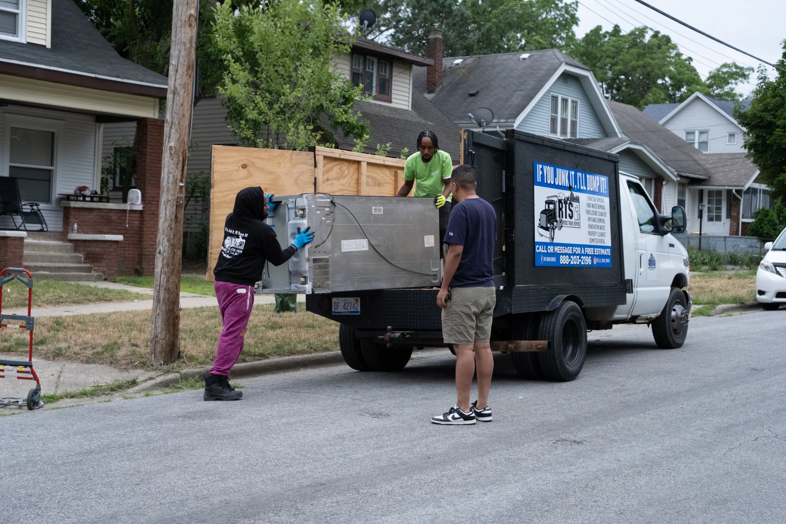 RTS Rocks Trash Service crew loading unwanted items into a branded junk-removal truck during a resid