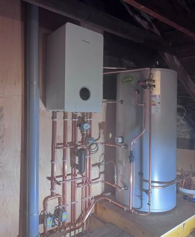 A residential boiler and water heater system with copper piping installed in an attic.