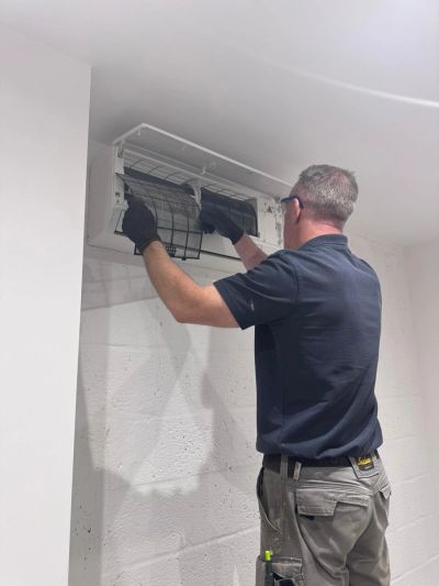 Technician cleaning an air conditioning unit filter indoors.