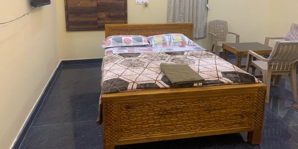 Cozy bedroom with wooden bed, patterned bedding, and a small seating area.
