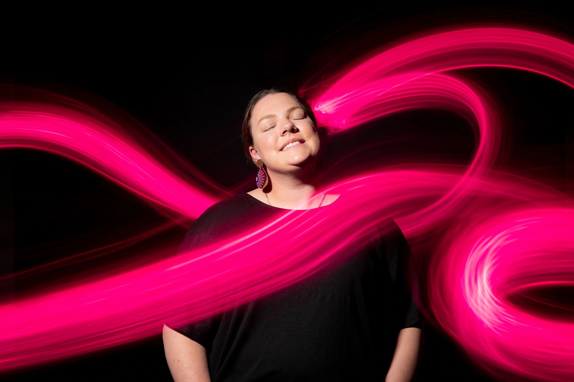 Woman smiling with pink bands of light surrounding her