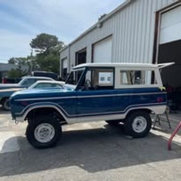 Classic blue and white vintage SUV parked outside a garage.