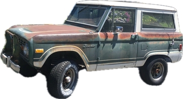 Old rusty Ford Bronco with faded paint and worn tires.