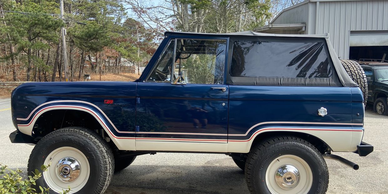 Classic blue and white vintage off-road vehicle with large tires and soft top.