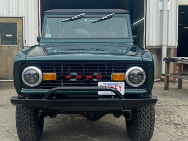 Classic green Ford Bronco with bold grille and rugged tires.