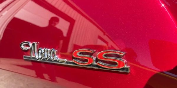 Close-up of a red Nova SS car emblem on shiny paint.