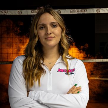 Young woman in white volleyball jacket with flames in the background.