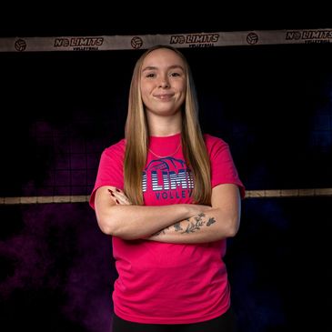 Young woman volleyball player with arms crossed, smiling confidently.