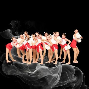 Young cheerleaders in red and white uniforms posing with pom-poms against a smoky black background.