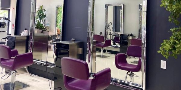 Modern salon with purple chairs and large mirrors in a stylish setup.